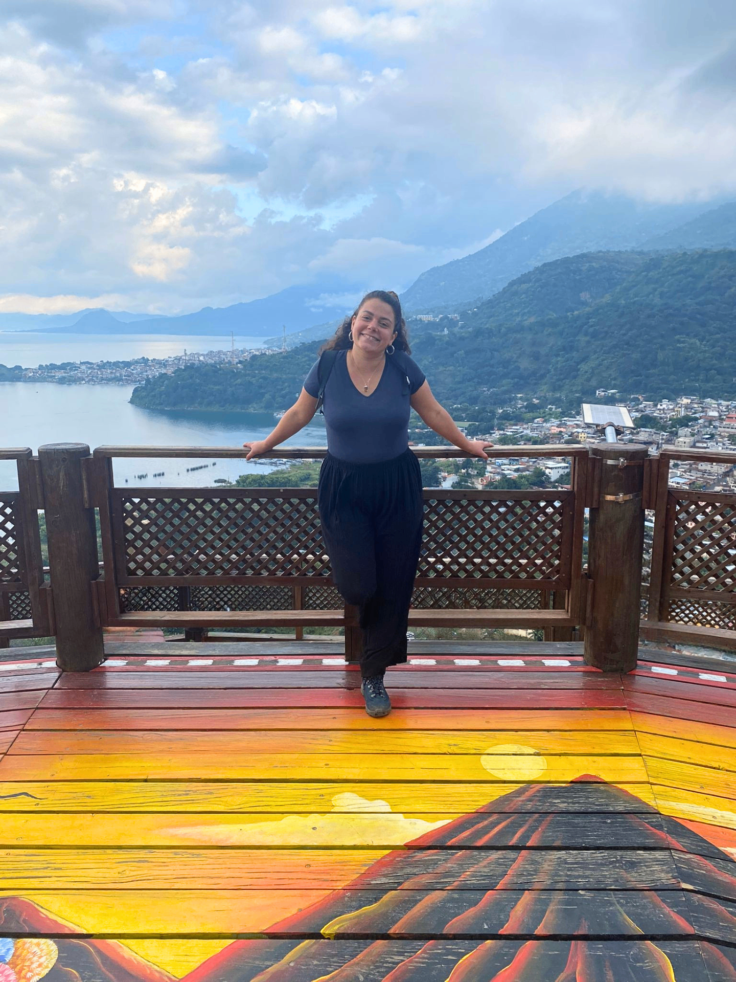 Justine sur une terrasse en bois face à un lac et des montagnes